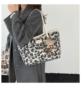 Detail of leopard print faux fur tote bag with beige leather straps and plush cat pendant