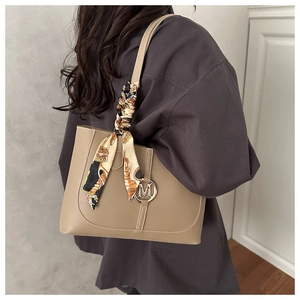 Detail of beige leather tote with golden M buckle and vintage crown pattern scarf