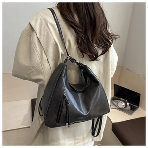 Details einer schwarzen Lederschultertasche mit Silberbeschlägen und Quaste am Modell