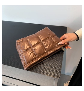 Détail d'une pochette matelassée marron avec finition métallique et fermeture éclair dorée