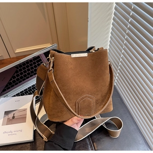 Detail of brown suede bucket bag featuring metallic trim and adjustable fabric strap