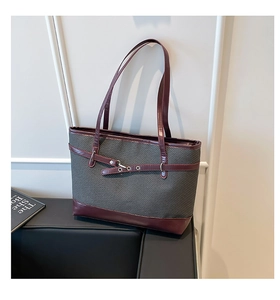 Close-up of contrast tote bag with dark grey woven texture and burgundy leather trim