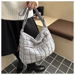Détail du sac cabas matelassé gris clair avec surpiqûres carrées et tissu brillant