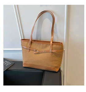 Close-up of contrast stitching on brown woven tote bag with adjustable leather straps