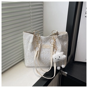 Détail du sac cabas crème avec tissu plissé texturé et anse en chaîne dorée élégante