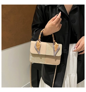 Detail of a chic crossbody bag with silk scarf handle and glitter texture contrast