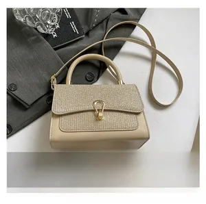 Detail view of cream handbag with sequined flap and gold metal buckle on grey blazer