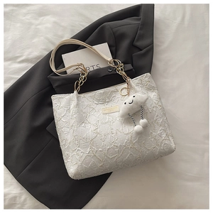 Détail du sac cabas blanc matelassé avec texture florale et bandoulière en chaîne dorée