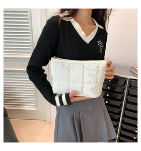Détail de la pochette matelassée blanche avec fermeture éclair et texture nylon doux