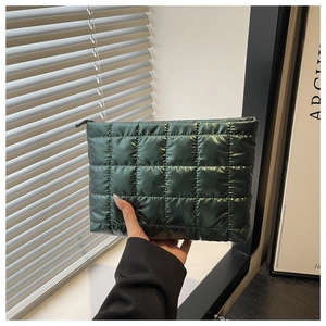 Gros plan d'une pochette matelassée vert foncé en nylon brillant avec fermeture à glissière