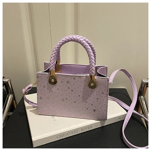 Detail of lavender star pattern bag with woven ring handle and gold hardware