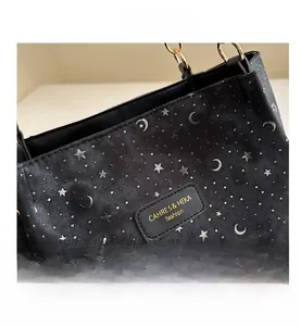 Detail of black canvas tote bag with silver star and moon print and leather logo patch