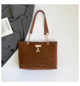 Dettaglio borsa tote leopardata con tracolla in pelle marrone e catena d'oro con ciondolo