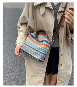 Close-up of a colorful woven straw tote with leather handles and adjustable shoulder strap