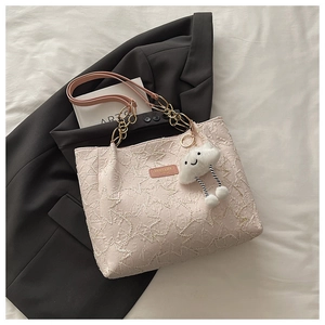 Détail du sac cabas brodé rose clair avec chaîne en métal et breloque nuage en peluche