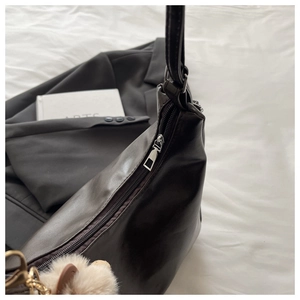 Detailaufnahme der schwarzen PU-Leder Tote Bag mit silbernem Reißverschluss und Bärenanhänger