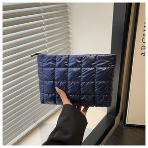 Détail de la pochette matelassée bleu marine avec finition brillante et fermeture éclair