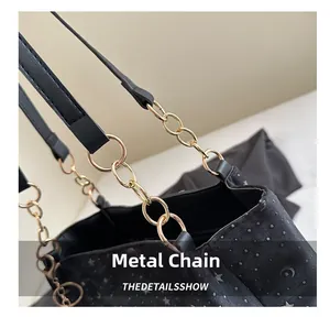 Close-up of golden metal chain straps and moon star patterns on the black tote bag