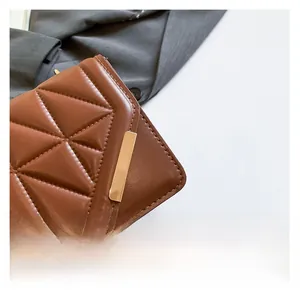 Detail of brown quilted leather bag with elegant stitching and golden metal clasp