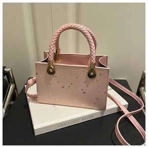 Detailed view of pink square handbag featuring silver stars and woven texture handles