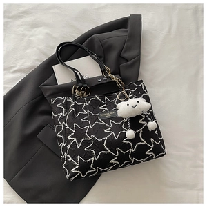 Détail du grand cabas noir avec coutures en étoile et charm nuage en peluche blanc