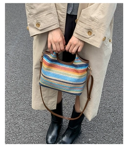 Detailed close-up of rainbow striped woven bag with leather handles and metallic hooks