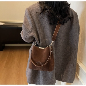 Detailed view of deep brown suede bucket bag with leather straps on a female model