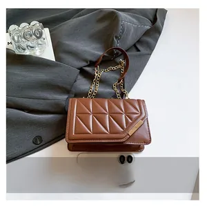 Close-up of brown quilted handbag showing size comparison with a mobile phone