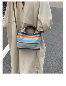 Detailed shot of a colorful striped woven straw bucket bag with leather strap on a model