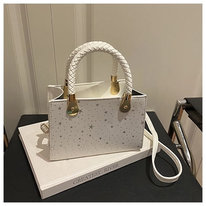 Close-up of white star-patterned tote bag with woven handles and golden metal hooks