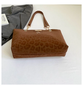 Dettaglio della borsa tote marrone leopardata con un ciondolo a forma di cervo dorato