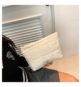 Détail d'une pochette matelassée blanche en nylon avec fermeture éclair dorée