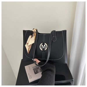 Detail of black matte tote bag featuring contrast stitching and a decorative silk scarf