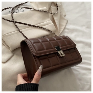 Detail of dark brown chocolate embossed leather bag with gold buckle and chain strap