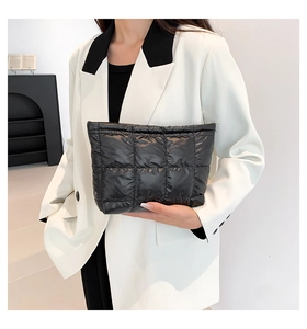 Pochette matelassée noire tendance tenue par un mannequin dans un décor intérieur épuré