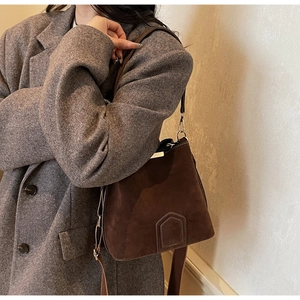 Detail of vintage brown suede bucket bag featuring elegant gold hardware and shoulder strap