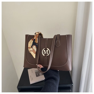 Brown leather tote bag detail with golden M logo and vintage silk scarf handle wrap