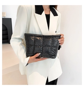 Détail de la pochette matelassée noire brillante montrant la texture et la fermeture éclair
