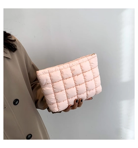 Detailansicht der rosa gesteppten Kosmetiktasche, gehalten von einem Modell im Mantel