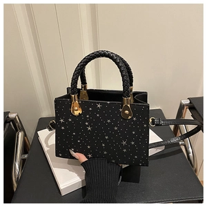 Detail of black tote with silver star studs, woven handles and golden metal hardware