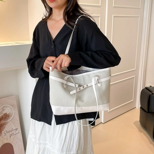 Chic grey woven tote bag with white leather trim and silver buckle shown on a model