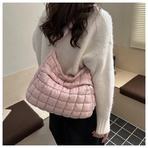 Détail de la texture matelassée rose du sac hobo et compartiment zippé porté