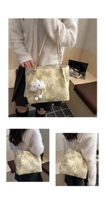 Detail of star-moon print tote bag with gold chain strap and plush cloud charm
