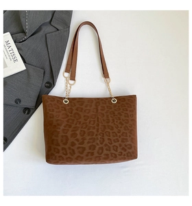 Dettaglio della borsa tote leopardata con spalline in pelle e ganci in metallo