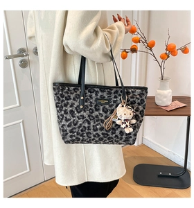 Detailed texture of leopard print plush tote bag with cat charm and leather handles