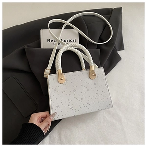 Detailed view of a white square handbag with silver star patterns and gold hardware