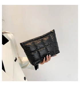 Détail macro d'une pochette matelassée noire avec fermeture éclair dorée à la main