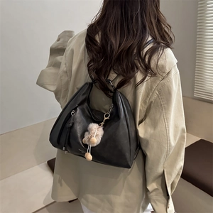 Schwarze Retro-Hobo-Tasche aus Leder mit beigem Pompon-Anhänger in der Rückansicht