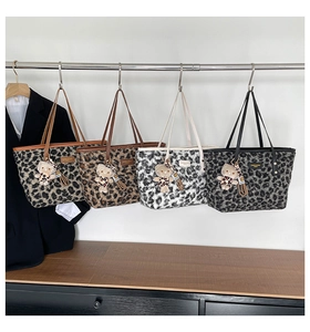 Detail of four leopard print plush tote bags with matching bear charms in various colors