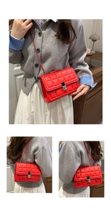 Detail of red quilted crossbody bag featuring silver square lock and chain strap texture